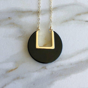 Sleek onyx coin stone suspended from a thin gold chain