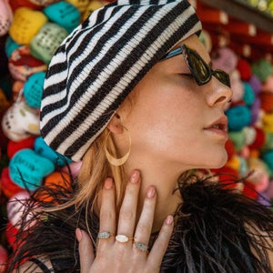 Model with beret and sunglasses wearing gold moon-shaped hoops