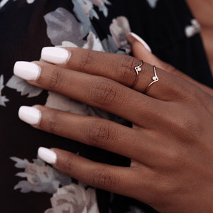 Hand model wearing two gold chevron shaped rings with tiny opal stones