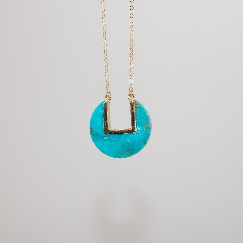 Model wearing blue coin-shaped necklace