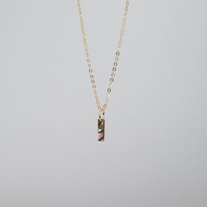 Small gold chain with an uppercase "I" made from abalone