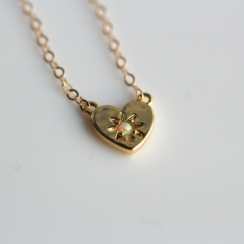 Gold heart charm necklace with a center opal stone