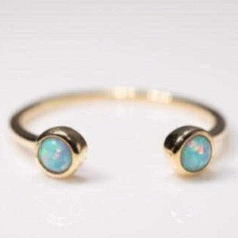 Gold cuff ring with two small round opal stones