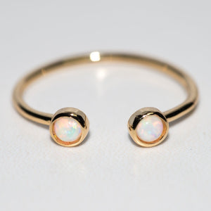 Gold cuff ring with two small round opal stones