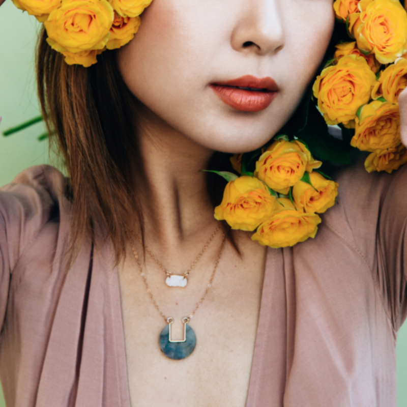 Model wearing blue coin-shaped necklace