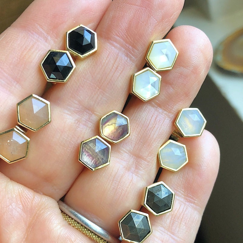 Six pairs of small hexagon studs displayed in hand